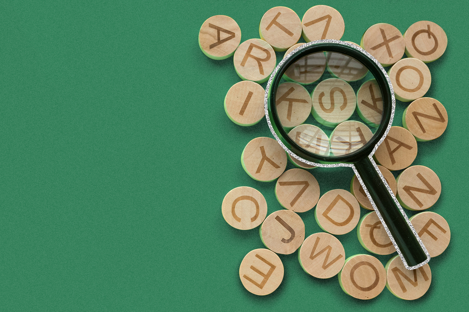 A magnifying glass sits atop circular pieces with letters on them.