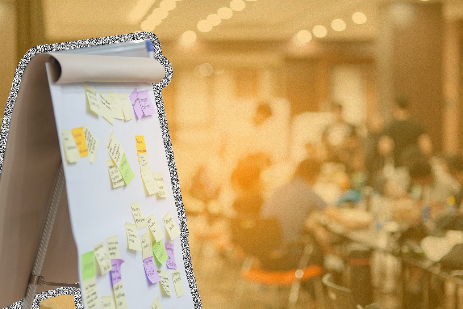 A large notepad with sticky notes in front of a group of people meeting