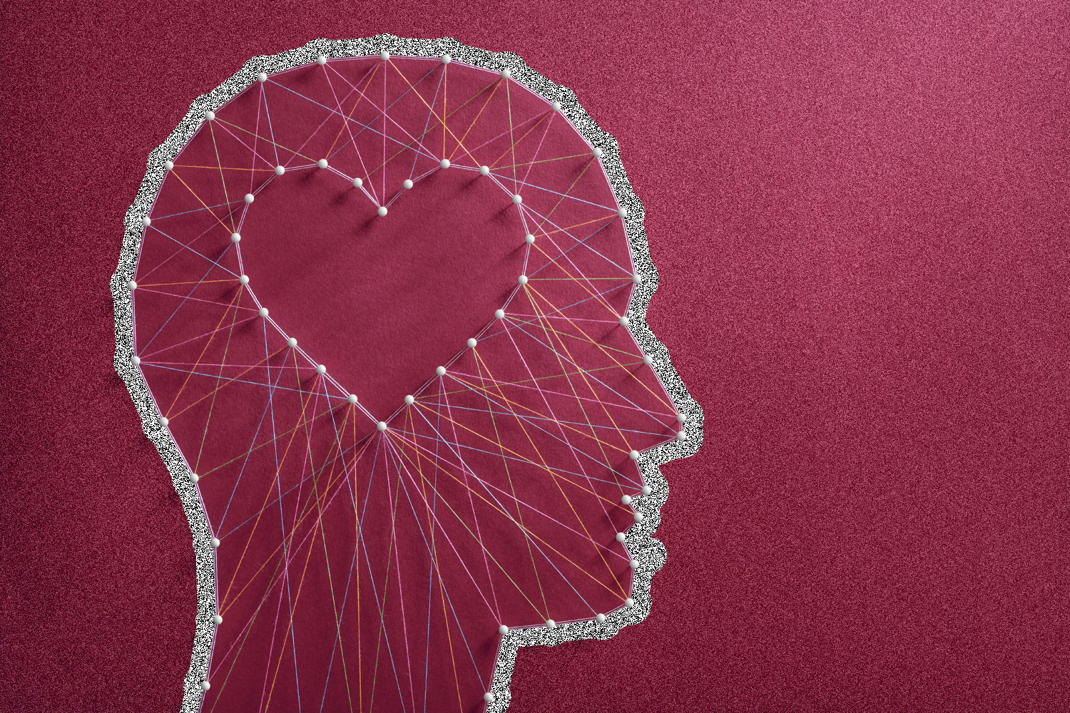 An outline of a person's head with pins and strings with a heart where their brain should be