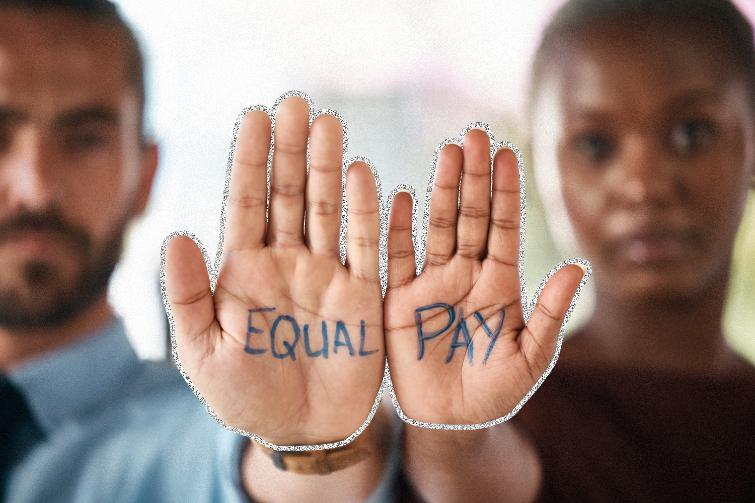 A man and a woman each holding a hand with "equal" and "pay" written on their palms.