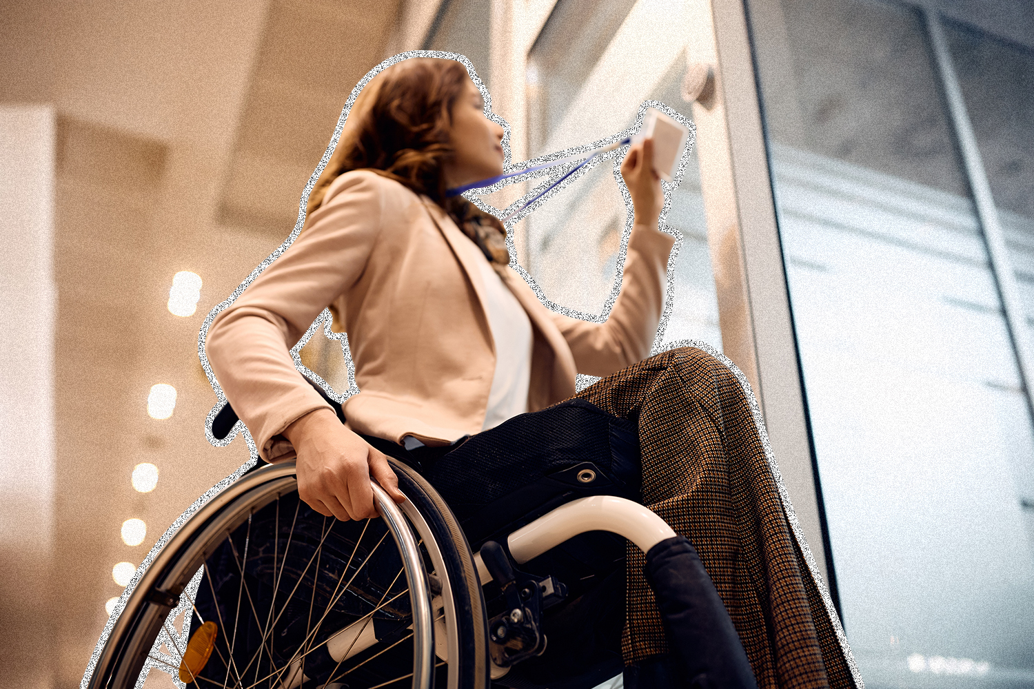 A woman in a wheelchair scanning a company badge to enter the door to an office.