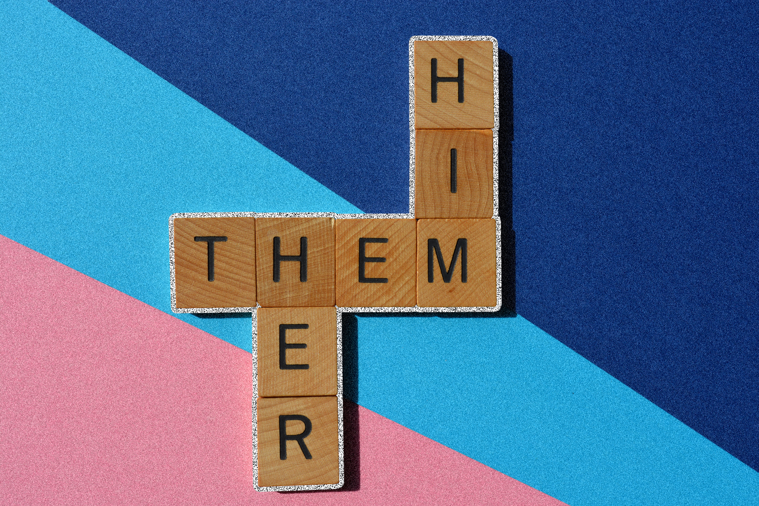 Wooden blocks with letters on them, placed together to spell "THEM," "HIM," and "HER.