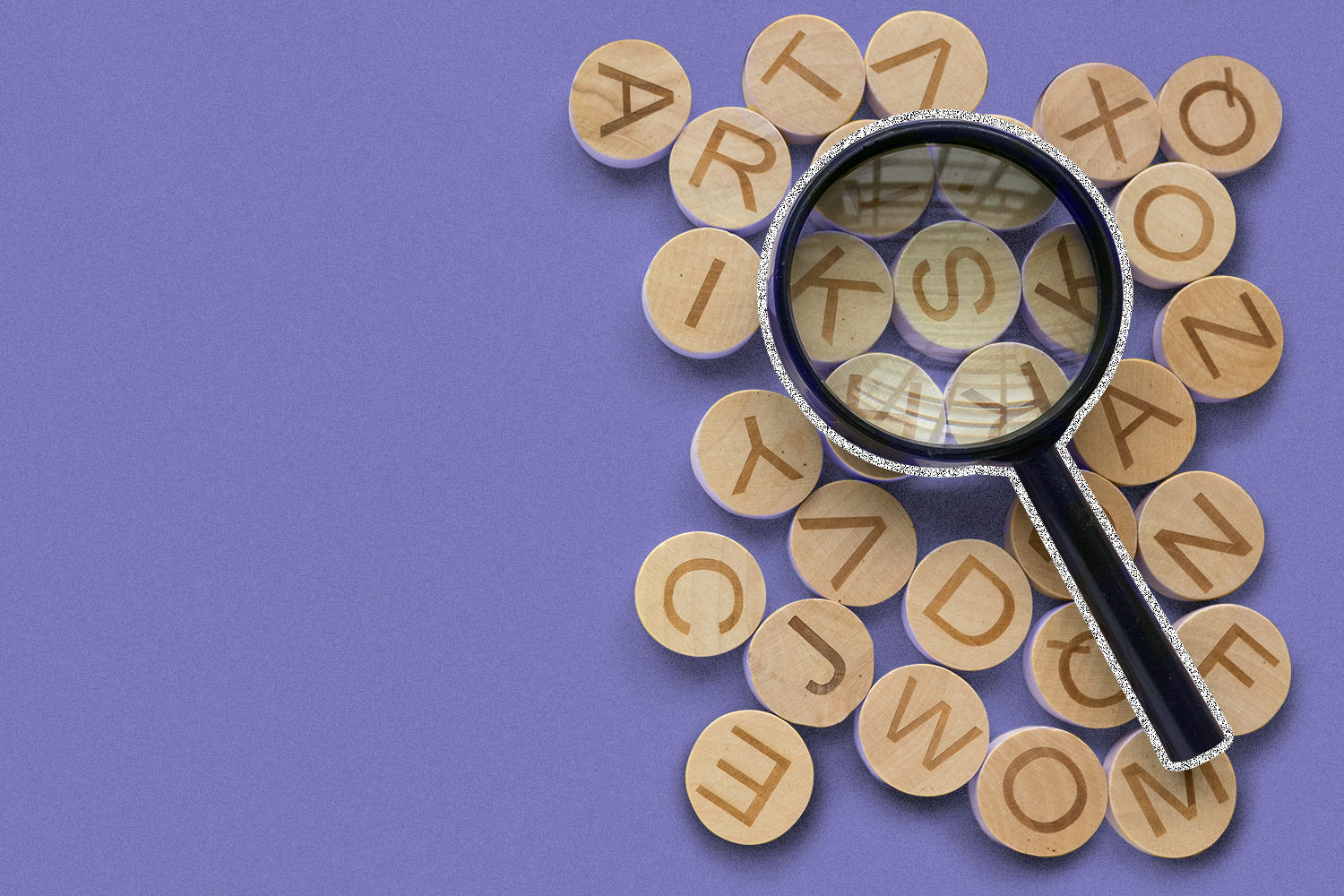 Round letter blocks on a purple background with a magnifying glass laying on top of the blocks.