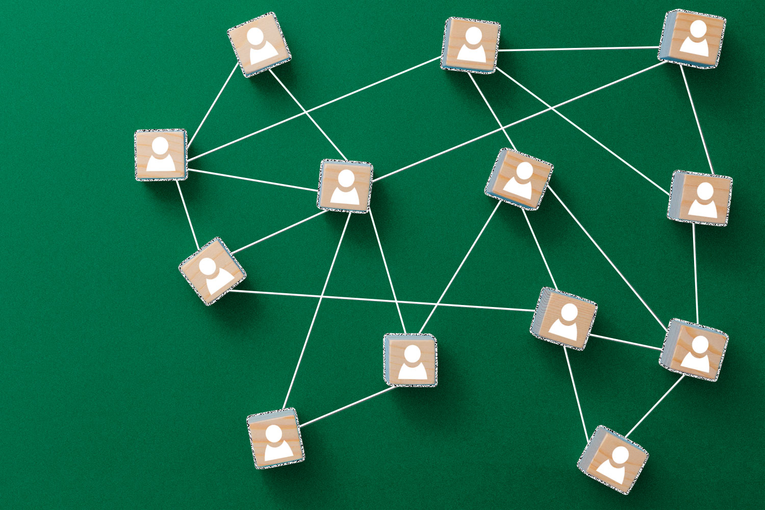 Square wooden blocks with people icons on them, connected by white lines to represent a network, on a green background