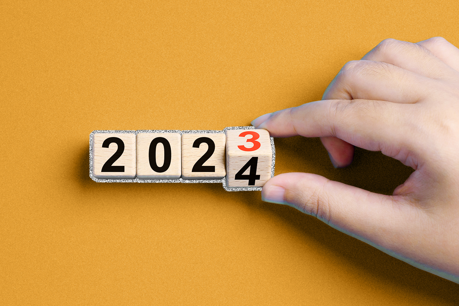 A hand is seen changing the year of a cube from 2023 to 2024.